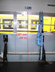 The figure is a photograph of the interior wall of a 2001 model year school bus.  The image is annotated with a vertical line showing the distance from the vehicle floor to the top of the window to be 1397 mm (55 in). 